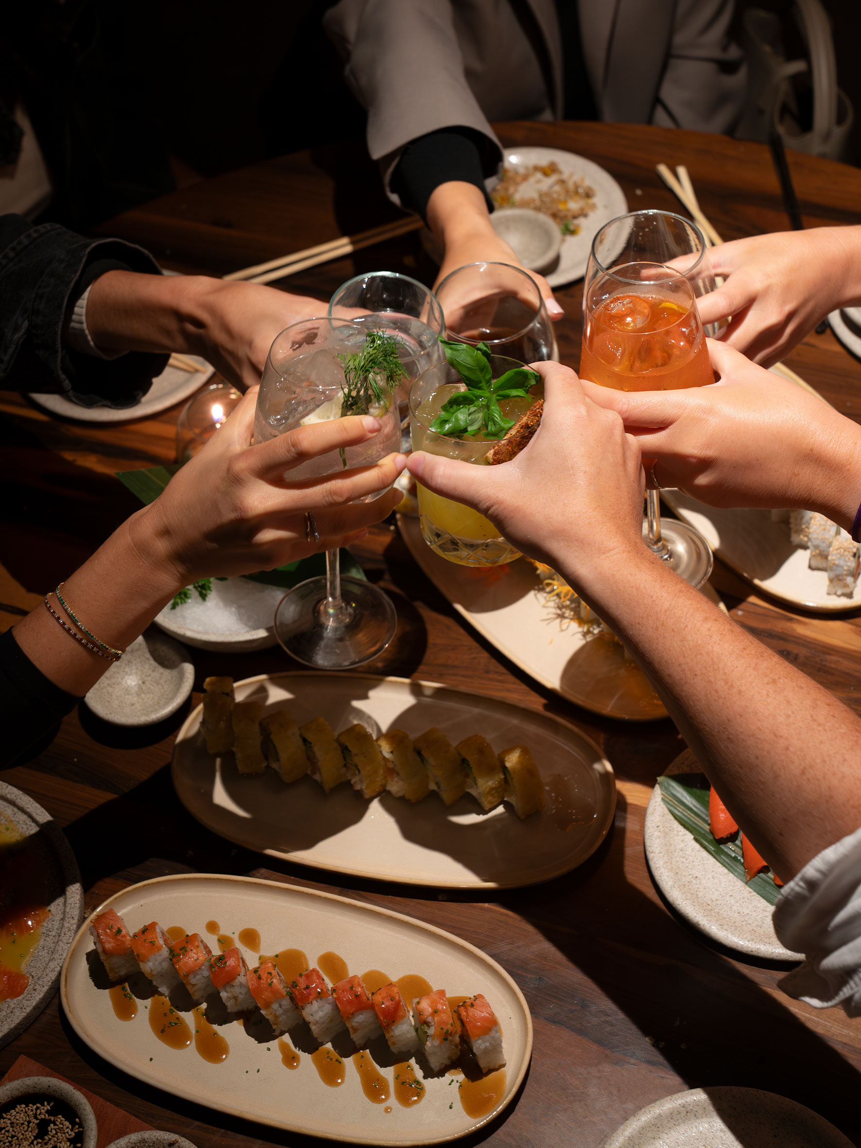 Brindis celebrando en mesa con sushi variado.